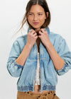 Woman wearing a light blue denim jacket on a white background