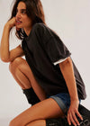 Woman in black oversized t-shirt and denim shorts posing against a plain background