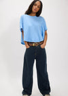 Person wearing a light blue oversized shirt and dark blue jeans on a white background