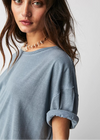 Woman wearing a light blue shirt with rolled-up sleeves against a plain background