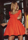 Woman wearing a bright orange dress with a blurred background