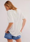 Person wearing a white oversized t-shirt and blue shorts on a plain background