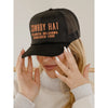 Black trucker hat with 'Cowboy Hat, Stillwater, Oklahoma, Established 1889' text held by a person.