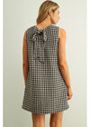 Woman wearing a black and white checkered dress against a light background