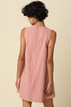 Person wearing a pink and white striped dress against a beige background