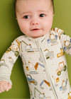 Baby wearing a onesie with vehicle patterns against a green background