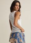 Woman wearing a white sleeveless top and blue floral skirt on a beige background