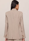 Person wearing a beige pinstripe suit against a plain background