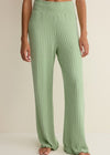 Green ribbed pants worn by a person on a neutral background