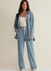 Woman wearing a denim jacket and pants on a beige background