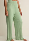 Green ribbed pants worn by a person on a beige background