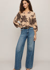 Woman wearing a floral sweater and blue jeans on a plain background