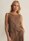 Woman wearing a brown sleeveless top and pants against a plain background
