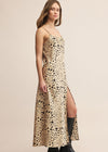 Woman wearing a leopard print dress with a slit on a beige background