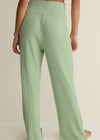 Green ribbed pants worn by a person on a beige background