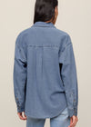 Person wearing a blue denim shirt against a beige background