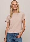 Woman wearing a beige t-shirt and blue jeans against a plain background